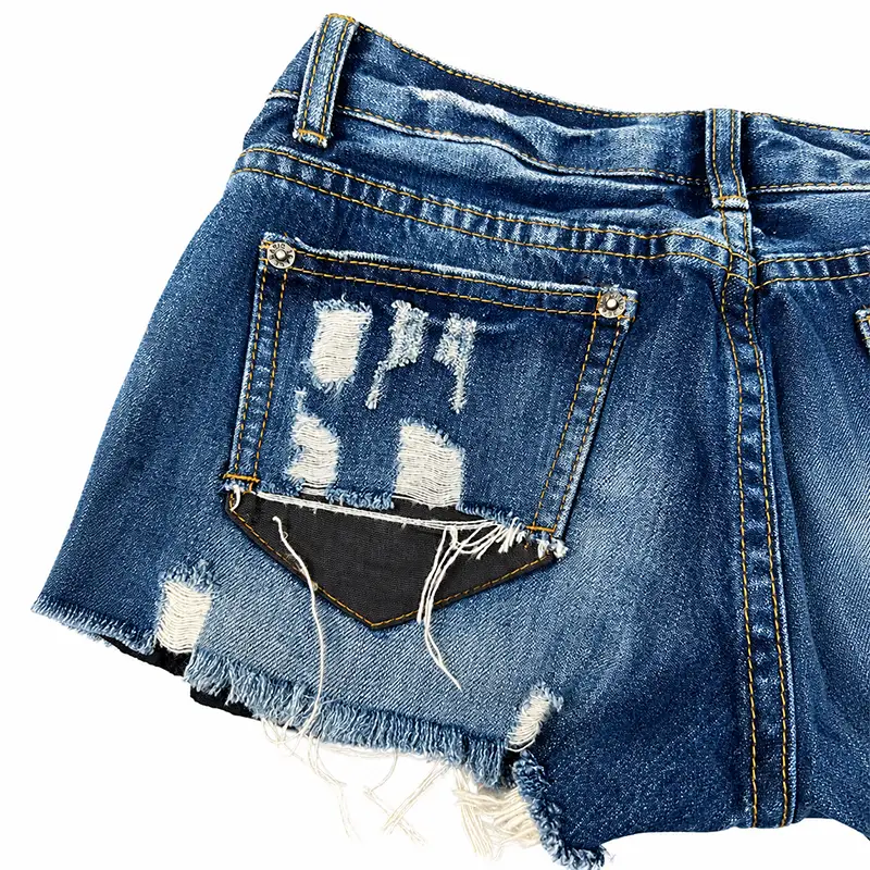 Back pocket detail of custom distressed denim shorts with ripped denim and black layered panels