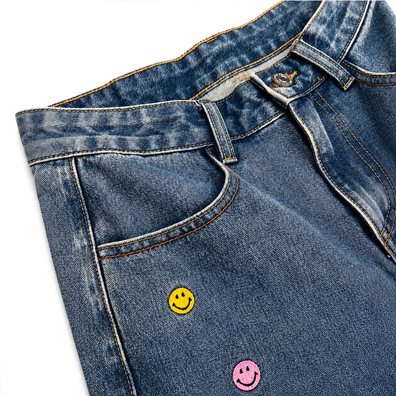 Waistband and pocket detail of custom wide leg denim jeans with yellow smile button